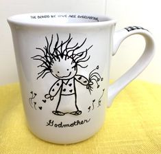 a white coffee mug with a drawing of a girl on the side and words above it