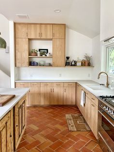 a kitchen with wooden cabinets and tile flooring in the middle of an open area