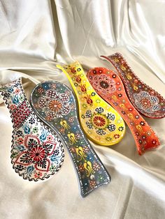 three decorative ceramic spoons sitting on top of a white cloth