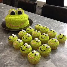 a table topped with cupcakes covered in green frosting and smiling face decorations