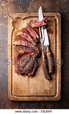 steak with knife and fork on cutting board