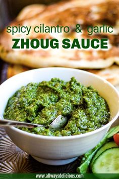 a white bowl filled with green sauce next to sliced cucumbers