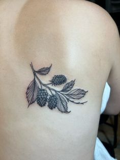 the back of a woman's shoulder with berries and leaves tattoo on her left side