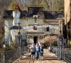 two people are standing in front of a building with a sign that says columbus's mysterious mansion