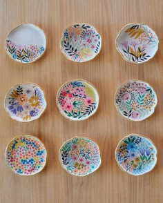 nine plates with different designs on them sitting on a wooden table next to each other