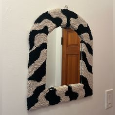 a mirror hanging on the wall with a black and white animal print frame around it