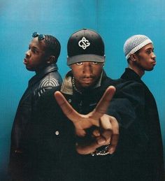 two young men standing in front of a blue wall making the v sign with their hands