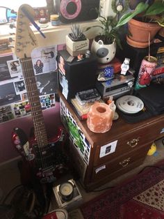 a guitar sitting on top of a wooden table next to a plant and other items