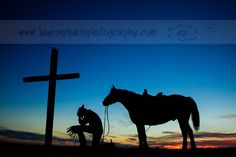 two horses standing next to each other in front of a cross and a person kneeling down