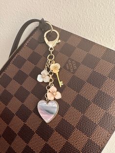 a purse with a keychain hanging from it's side on top of a checkered surface