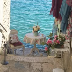 a table and chairs sitting on the side of a building next to some blue water