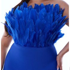 a woman wearing a blue dress with feathers on it