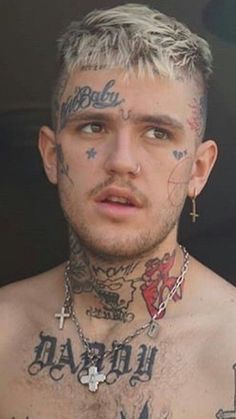 a man with tattoos and piercings on his chest is looking at the camera while wearing a chain around his neck