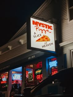 a sign that says mystic pizza on the side of a building with neon signs above it