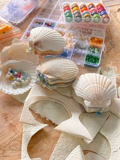 seashells, beads and other crafting supplies are on a wooden table top