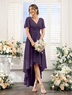 a woman standing in front of flowers wearing a purple bridesmaid dress with short sleeves