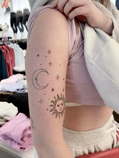 a woman with a tattoo on her arm is looking at the sun and moon tattoos