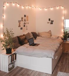 a bed with a laptop on top of it in a room that has lights strung from the ceiling