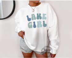 "If you're heading out on the boat for a day of fishing, waterskiing, roasting marshmallows around the campfire, or simply lounging on the deck with a good book, this \"Lake Girl\" sweatshirt is the perfect choice for any lake-loving girl. This cute Lake Girl sweatshirt will add a touch of cute and cozy style to your next lakeside adventure! Makes the perfect gift. , ♥ A Tomorrows Look Today Signature Design - this item is MADE TO ORDER just for you! ♥ Our graphic sweatshirts are very soft, very Lake Bachelorette, Lake Life Shirt, Lake Girl, Babe Shirt, Around The Campfire, Girls Trip Shirts, Roasting Marshmallows, Cozy Style, Trendy Collection