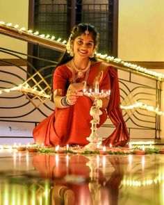 a woman sitting on the ground holding a lit candle