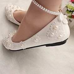 a close up of a person wearing white shoes with pearls on the heel and ankle