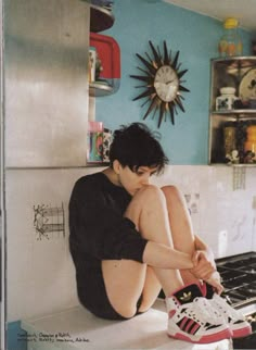 a young man sitting on the kitchen counter with his feet up in front of him