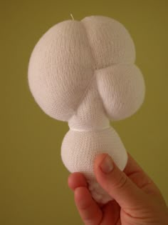 a person holding up a white object in their hand, with the top part of it made out of knitted material