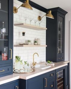 a kitchen with dark blue cabinets and brass fixtures, white subway tile backsplash