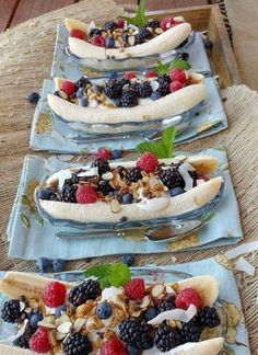 three plates with bananas, berries and nuts on them