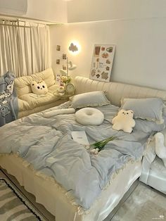 a bed with stuffed animals on it in a room next to a couch and window