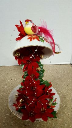 a white vase with red flowers and a yellow bird on it's top sitting on a plate