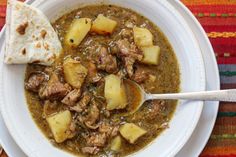 a white bowl filled with stew and some tortilla bread on top of it