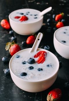 two bowls filled with yogurt and strawberries on top of a black table