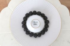 a white plate topped with blackberries on top of a table