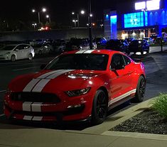 a red sports car parked in front of a gas station at night with its lights on