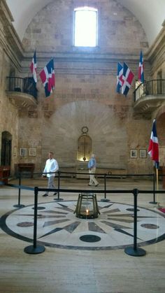 two men are walking in the middle of a room with flags hanging from the ceiling