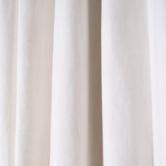 a close up view of a white curtain with the curtains pulled back to reveal light