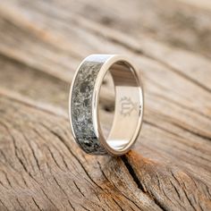 a wedding ring with antler wood inlays the center on a wooden surface