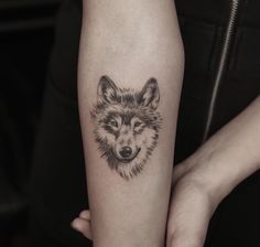 a woman's arm with a tattoo of a wolf on the left inner forearm