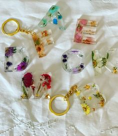 a bunch of flowers are sitting on a white sheet with gold keychains and charms