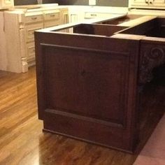 an empty kitchen with wooden floors and white cabinets in the center, is shown from the front