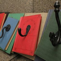 four books are lined up on a couch with an iron hook attached to the book ends