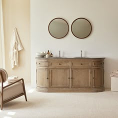 a bathroom with two circular mirrors on the wall and a chair in front of it