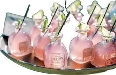 small pink bottles with flowers in them are lined up on a metal tray for display