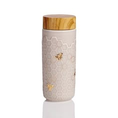 a ceramic jar with bees and honeycombs painted on it's sides, sitting on a white surface