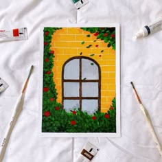 some paint and brushes are laying on a table with an image of a brick wall