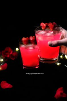 a person is holding a glass with some fruit on the rim and strawberries in it