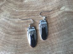 two pairs of earrings sitting on top of a piece of wood with silver ear wires