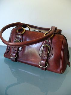 This bag is in wonderful condition. It is very clean and with only one  visible issue. The leather is worn through at the piping on one corner. It has been very gently used. Measures 7" x 10.5" x 4" Handle Drop 8" Please measure carefully and feel free to ask more questions as there are  no refunds or exchanges. Lot  BR r-11 Doctor Style, Chestnut Brown, Chestnut, Piping, Duffle Bag