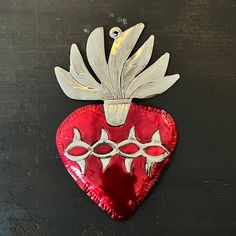 a red heart shaped object with silver decorations on it